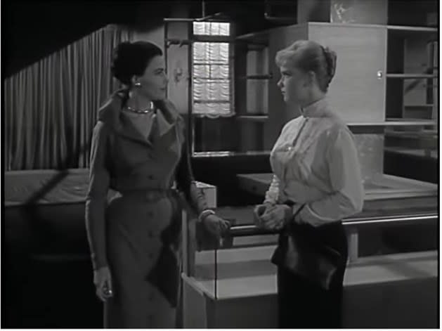 Two women stand talking by a department store counter