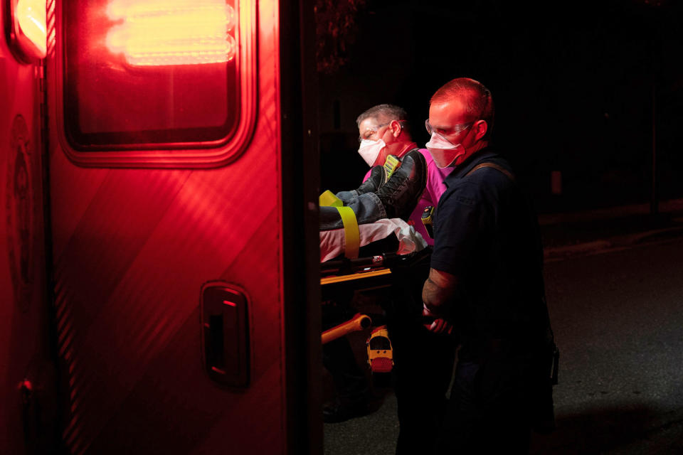 Firefighters and paramedics with Anne Arundel County Fire Department wear enhanced protective equipment as they load a patient into an ambulance on Oct. 26, 2020 in Glen Burnie, Md. (Alex Edelman / AFP - Getty Images)