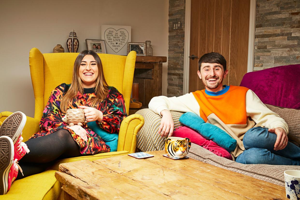  Pete and Sophie sitting on the sofa and smiling at the camera. 