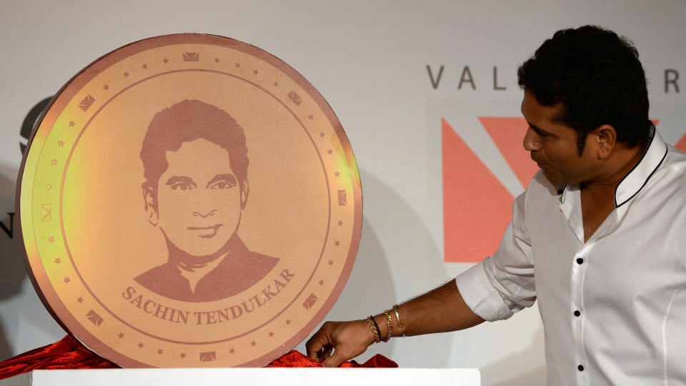 Indian cricketer Sachin Tendulkar looks at large model of a limited edition 10 gram gold coin with an embossed image of himself after unveiling it on Akshaya Tritiya in Mumbai on May 13, 2013. A total of 100, 000 limited edition 10 gram Tendulkar Gold coins priced at INR 34,000 (USD 618) will be available for both online purchase and at retail stores of leading jewellers across the country. Akshaya Tritiya is considered to be an auspicious day in the Hindu calendar to buy valuables and people generally flock to buy gold on this day in the belief that it will increase their wealth. AFP PHOTO/ Indranil MUKHERJEE