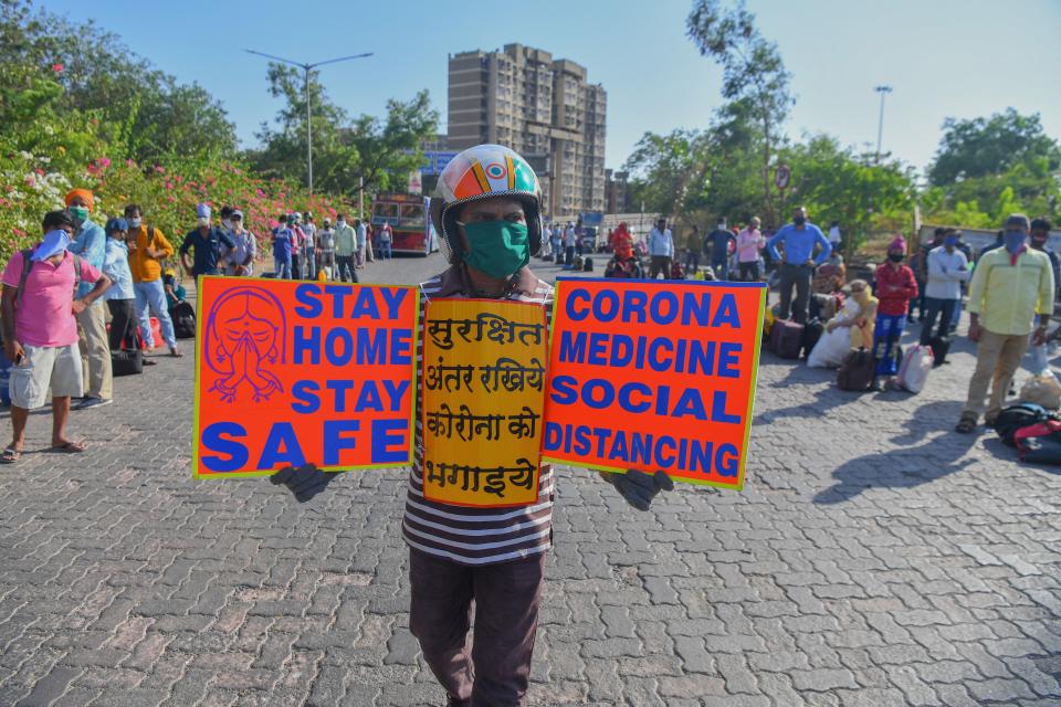 <p>Social worker Surender holds placards to create awareness about social distancing among migrant workers</p>AFP via Getty Images