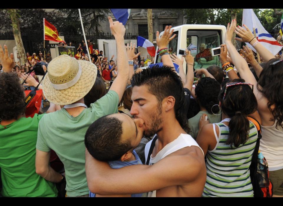 A gay couple kisses as Pope Benedict XVI (R) waves to faithful from his popemobile on his way to Cibeles square in Madrid, on Aug. 18, 2011, before a welcoming ceremony. 