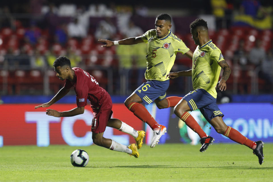 Qatar's Akram Afif, left, falls followed by Colombia's William Tesillo, center, and Wilmar Barrios during a Copa America Group B soccer match at the Morumbi stadium in Sao Paulo, Brazil, Wednesday, June 19, 2019. (AP Photo/Victor R. Caivano)