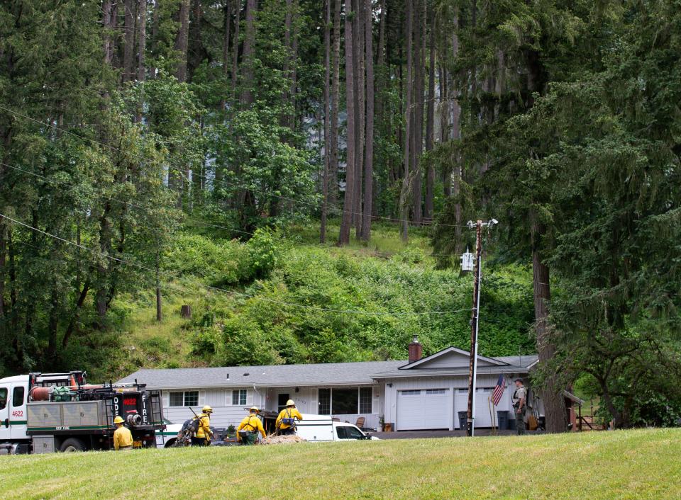 Firefighters with Pleasant Hill Goshen Fire make their way into the forest above a home on Cedar Hills Drive to nearby Cedar Hill Fire south of Pleasant Hill.