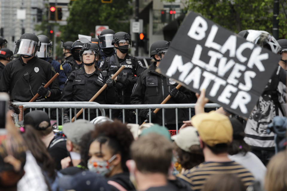 FILE - In this June 3, 2020, file photo, police officers behind a barricade look on as protesters fill the street in front of Seattle City Hall, in Seattle, following protests over the death of George Floyd, a black man who was in police custody in Minneapolis. The King County Labor Council, the largest labor group in the Seattle area, vote Wednesday night June 17 to expell the city’s police union, saying the guild representing officers failed to address racism within its ranks. (AP Photo/Elaine Thompson, File)