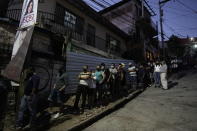 People line up outside a polling station after closing time to vote during general elections in Tegucigalpa, Honduras, Sunday, Nov. 28, 2021. The National Electoral Council announced that polling stations that still had people waiting outside to vote should stay open until all had a chance to cast their ballots. (AP Photo/Moises Castillo)