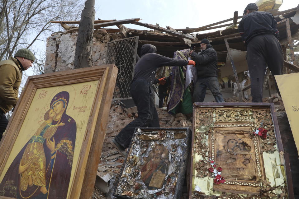 CAPTION CORRECTS TOWN SPELLING - People save icons as they clear the rubble after a Russian rocket ruined an Orthodox church in rocket attack on Easter night, a crater left by the rocket in the foreground, in Komyshuvakha, Zaporizhzhia region, Ukraine, early hours Sunday, April 16, 2023. (AP Photo/Kateryna Klochko)