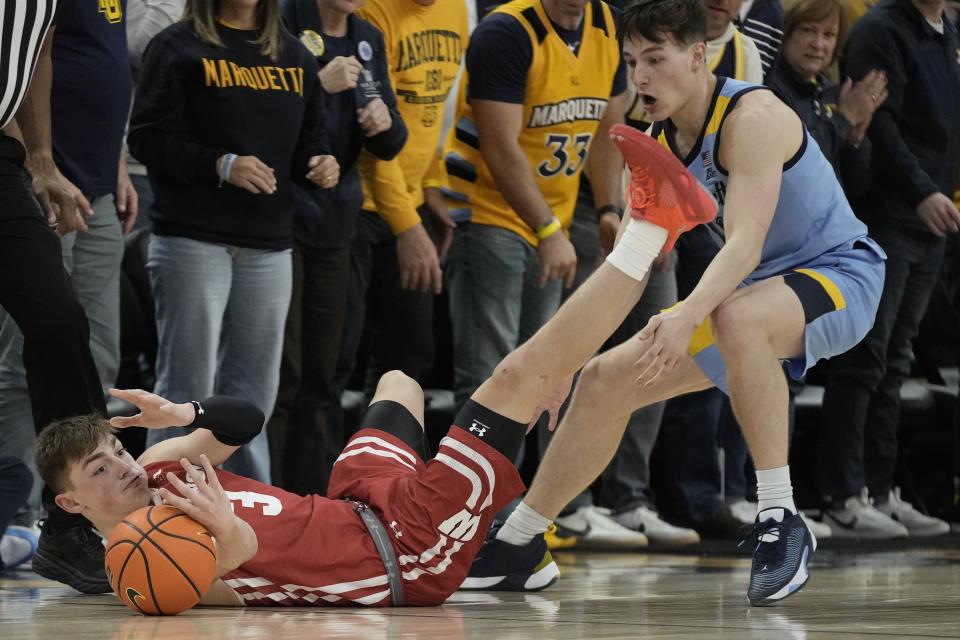 Wisconsin's Connor Essegian and Marquette's Tyler Kolek go after a looose ball during the second half of an NCAA college basketball game Saturday, Dec. 3, 2022, in Milwaukee. Wisconsin won 80-77 in overtime. (AP Photo/Morry Gash)