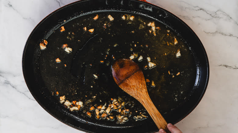 Wooden spoon stirring sauce in pan