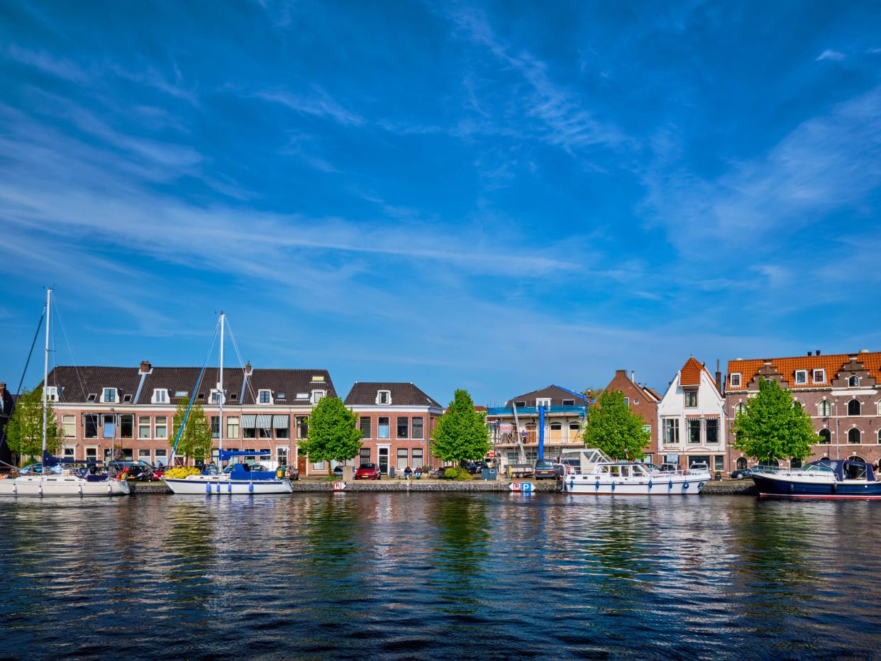 Boats and houses on Spaarne river with blue sky. Haarlem, Netherlands