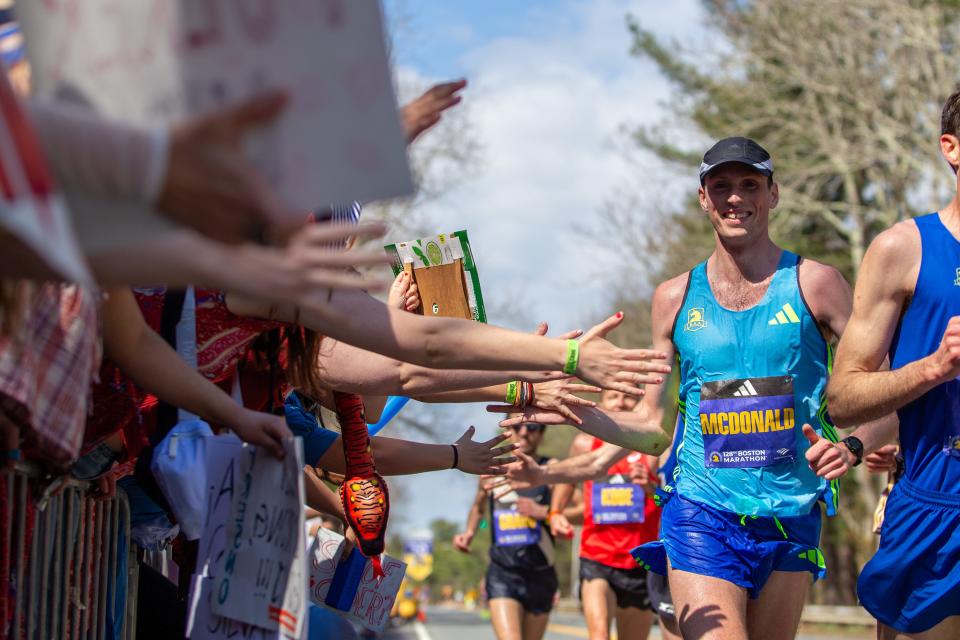 Matthew McDonald, a men's elite runner from Cambridge, slaps hands with the crowd near the Boston Marathon's halfway point at Wellesley College, April 15, 2024.