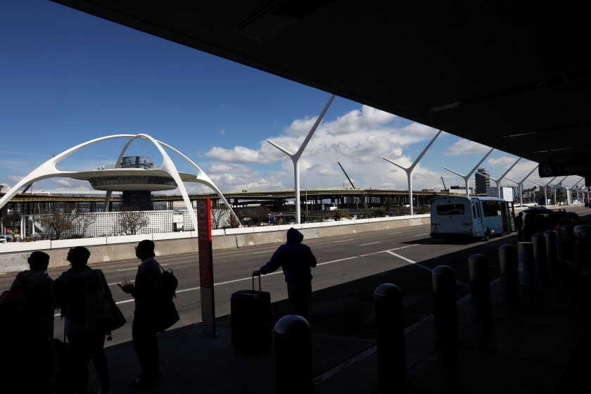 LOS ANGELES, CA - MARCH 12, 2021 - - Travelers wait curbside at Terminal 6 at Los Angeles International Airport near the one-year anniversary of the coronavirus pandemic on March 11, 2021. A year ago LAX was almost a ghost town due to the pandemic shutdown. Travelers have been returning to the airport since but is still light compared to pre-pandemic days. (Genaro Molina / Los Angeles Times)