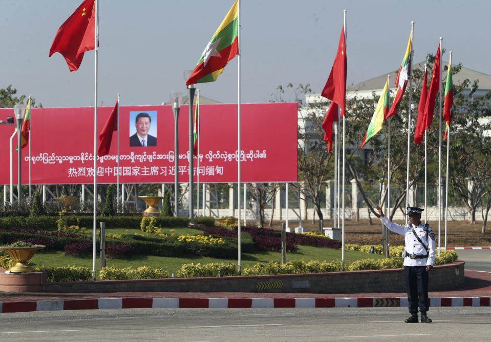 A traffic police stands on a road as he clears a road near a welcoming billboard to Chinese President Xi Jinping Friday, Jan. 17, 2020, in Naypyitaw, Myanmar. China's President Xi Jinping was heading to Myanmar on Friday for a state visit likely to deepen the countries' already close bilateral relations at a critical time. (AP Photo/Aung Shine Oo)