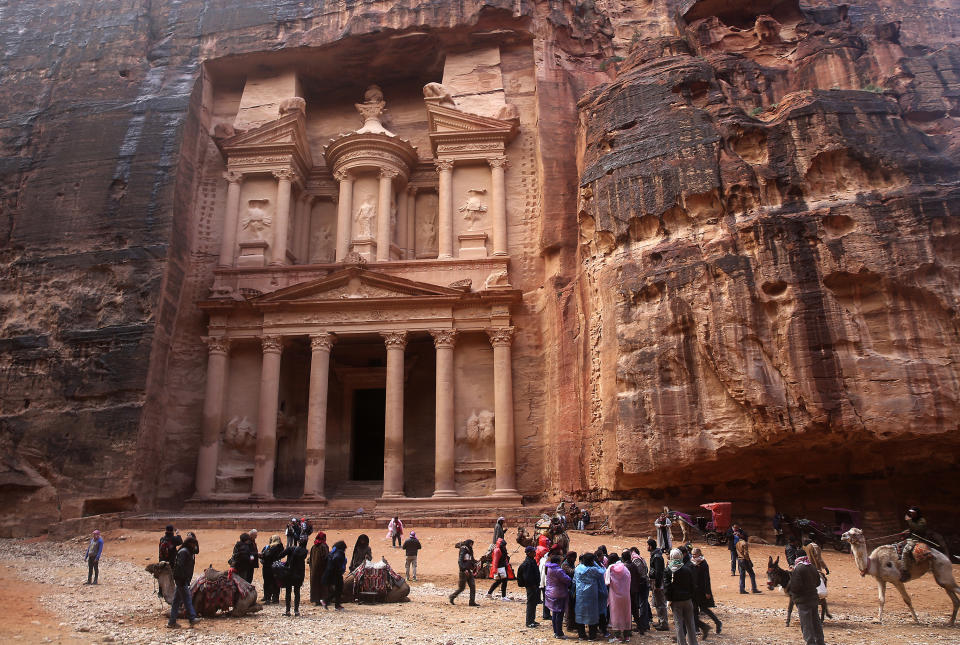 FILE - In this Feb. 13, 2017, file photo, tourists brave a rare rainstorm in plastic ponchos to peer at the Treasury, Jordan's most famous archaeological monument leftover from the Nabatean civilization in the kingdom's Petra archaeological park. Flash floods caused by heavy rain across Jordan killed people Friday, Nov. 9, 2018 and forced hundreds of tourists to seek higher ground in the kingdom's ancient city of Petra, the government spokeswoman said. (AP Photo/Sam McNeil, File)