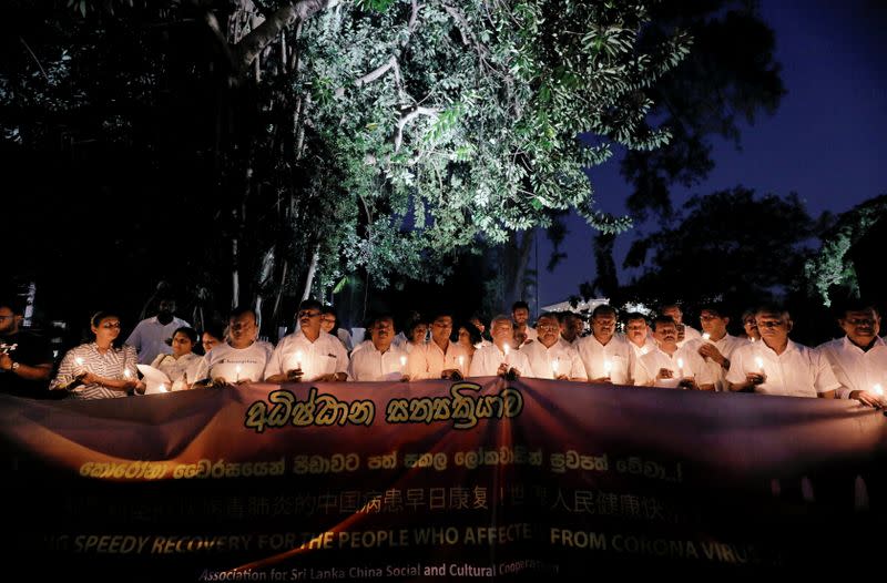 Members of the Association for Sri Lanka-China Social and Cultural Cooperation (ASLCSCC) hold candles during a vigil to pray for people who are suffering from the coronavirus in the world in Colombo