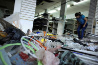 <p>A worker looks for valuables among the damaged goods in a store after it was looted, in La Fria, Venezuela, Dec. 19, 2016. (Carlos Eduardo Ramirez/Reuters) </p>