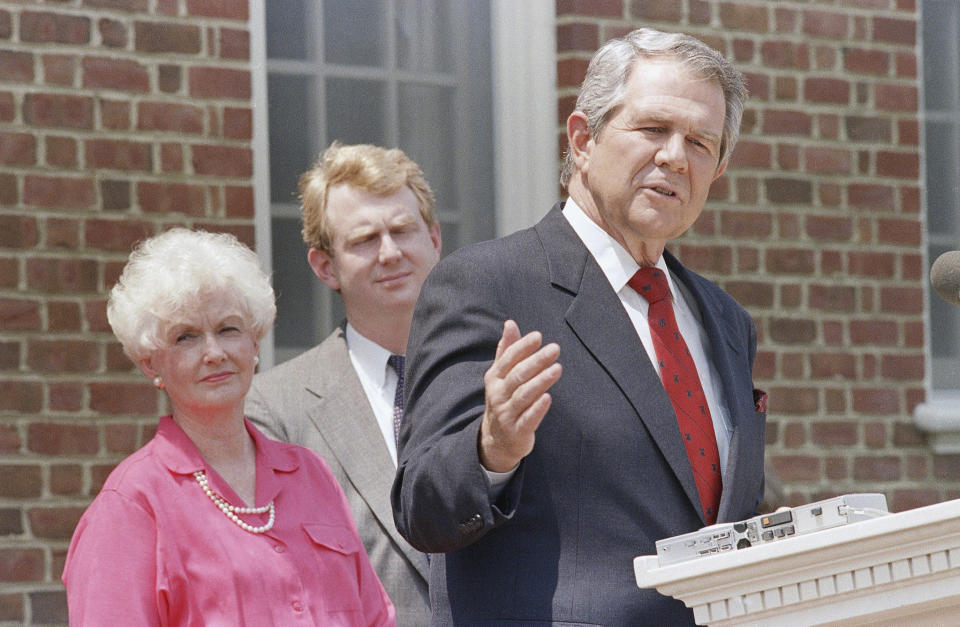 FILE - Former Republican presidential contender Pat Robertson gestures as he announces that he is suspending his campaign during a news conference, May 16, 1988, at his home in Virginia Beach, Va. Listening to Robertson are his son Tim and wife Dede. Robertson, a religious broadcaster who turned a tiny Virginia station into the global Christian Broadcasting Network, tried a run for president and helped make religion central to Republican Party politics in America through his Christian Coalition, has died. He was 93. Robertson's death Thursday, June 8, 2023 was announced by his broadcasting network. (AP Photo/Steve Helber, File)