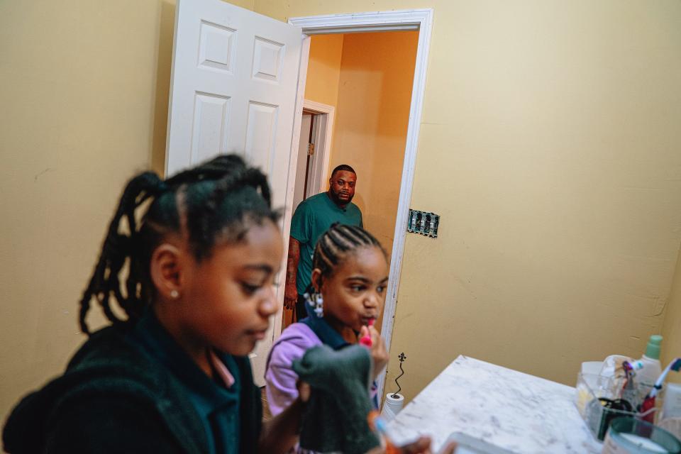 Jeremiah's daughters, Janae and Peyton, brush their teeth as their father gets ready to bring them to school. For months after leaving the police department, he did not tell his youngest kids he was out of work.