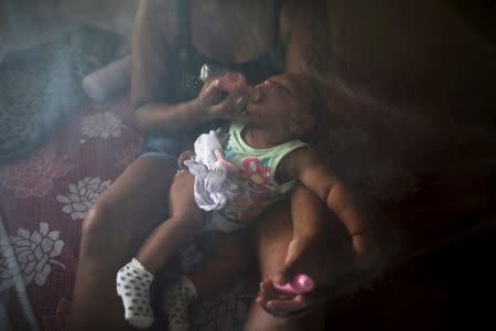 Vanessa, 32, feeds her daughter Valentina who is 5-months old and born with microcephaly, with a bottle under a mosquito net, inside their house in Jaboatao, near Recife, Brazil, February 12, 2016. REUTERS/Nacho Doce