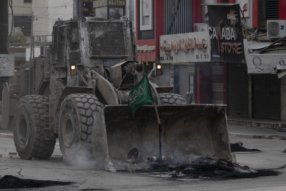 A bulldozer from the Israeli forces removes a Hamas militant group flag from a street during clashes with Palestinian demonstrators in the West Bank city of Jenin, Wednesday, May 22, 2024. (AP Photo/Leo Correa)