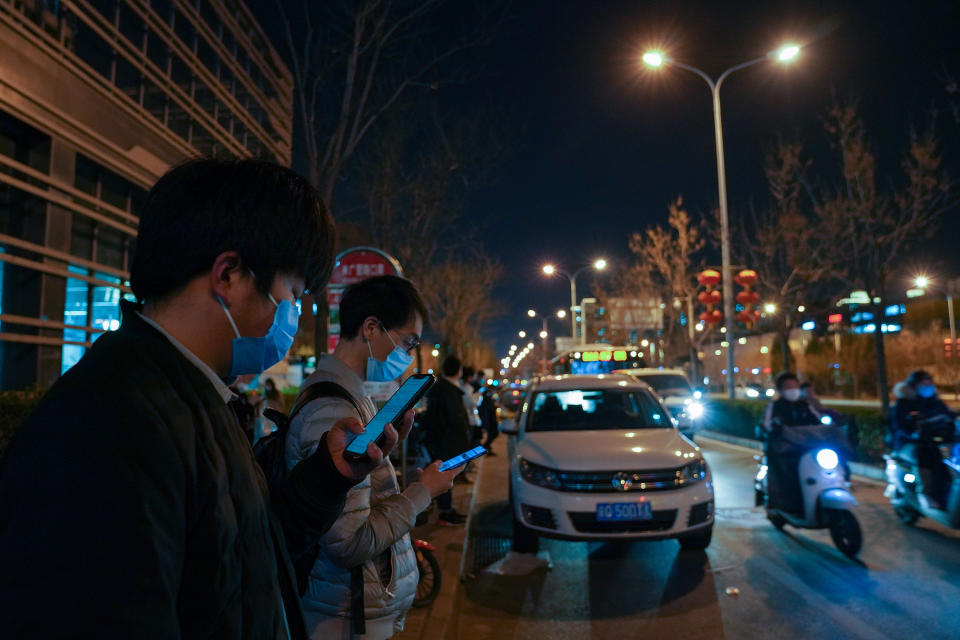 La mayoría de casos registrados en los últimos días son importados. En la imagen, unas personas miran sus teléfonos móviles mientras esperan el autobús en una calle de Pekín. (Foto: Lintao Zhang / Getty Images).