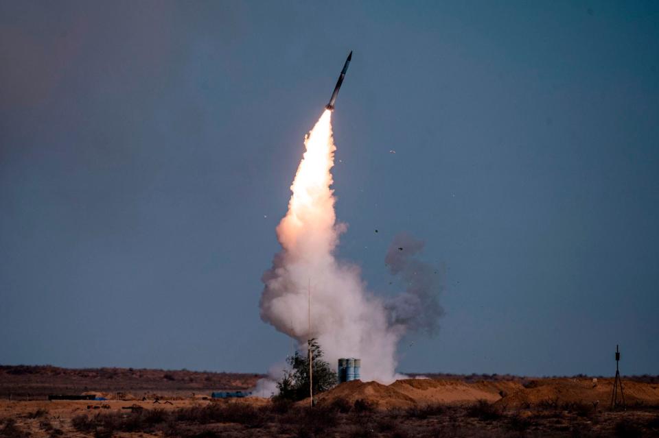 A rocket launches from a S-400 missile system against a dark blue sky