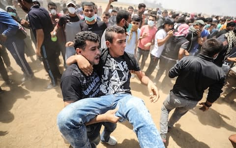 Palestinians carry an injured protestor near the Gaza-Israel border at Khan Yunis - Credit: Mustafa Hassona/ Anadolu