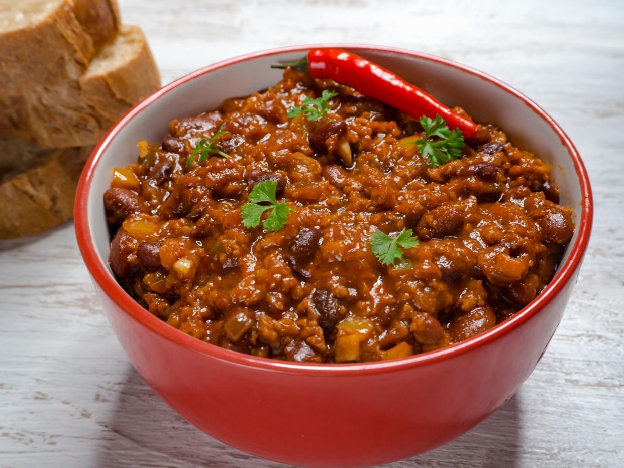 Chili con carne in bowl on white wooden background. Mexican traditional dish