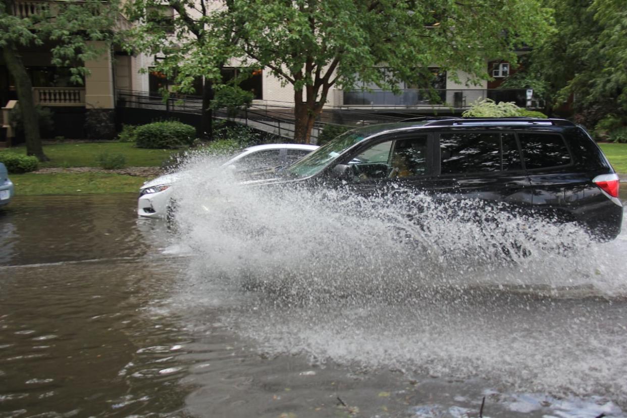 A car moving through a massive puddle on Crawford Avenue after a brief but heavy thunderstorm on Friday, July 28, 2023.  (Mike Evans/CBC - image credit)