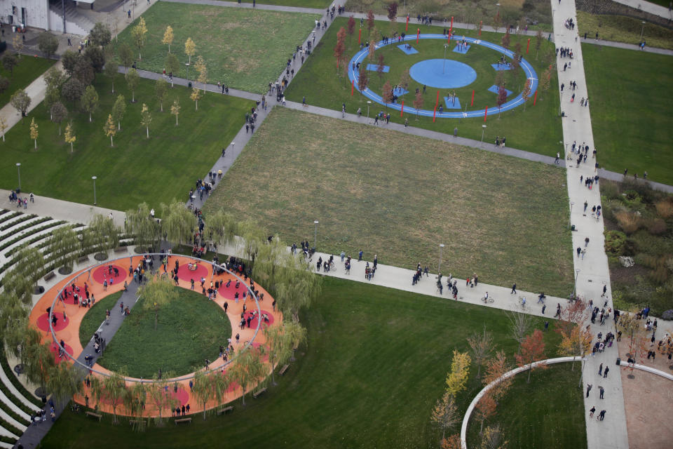 In this picture taken on Saturday, Oct. 27, 2018 people walk in the 'Tree Library' park, in Milan, Italy. If Italy's fashion capital has a predominant color, it is gray not only because of the blocks of uninterrupted neoclassical stone buildings for which the city is celebrated, but also due to the often-gray sky that traps in pollution. The city has ambitious plans to plant 3 million new trees by 2030_ a move that experts say could offer relief to the city’s muggy and sometimes tropical weather. (AP Photo/Luca Bruno)