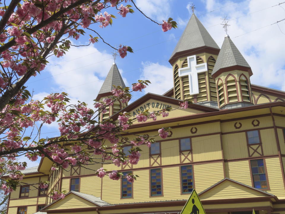 Flowering tree blossoms frame the Great Auditorium in Ocean Grove, N.J. on May 2, 2024. The state of New Jersey says the Ocean Grove Camp Meeting Association is violating state beach access laws by keeping people off the beach until noon on Sundays. (AP Photo/Wayne Parry)