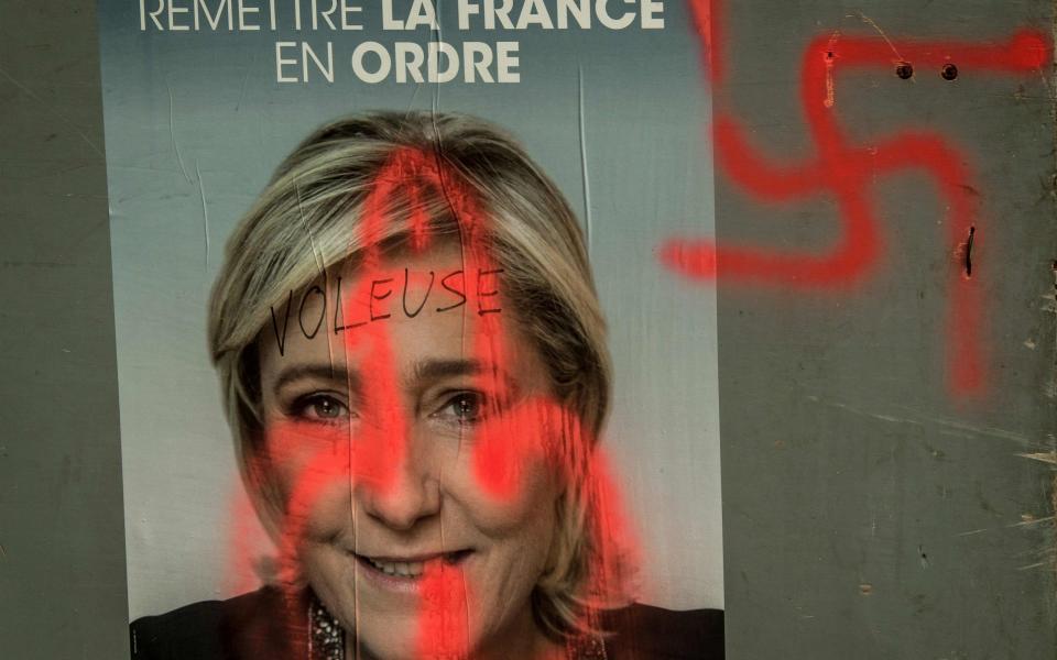 A campaign poster of the far-right Front National candidate Marine Le Pen covered with graffiti, in Caestre, northern France, two days before the first round of the election. - Credit: Philippe Huguen/AFP