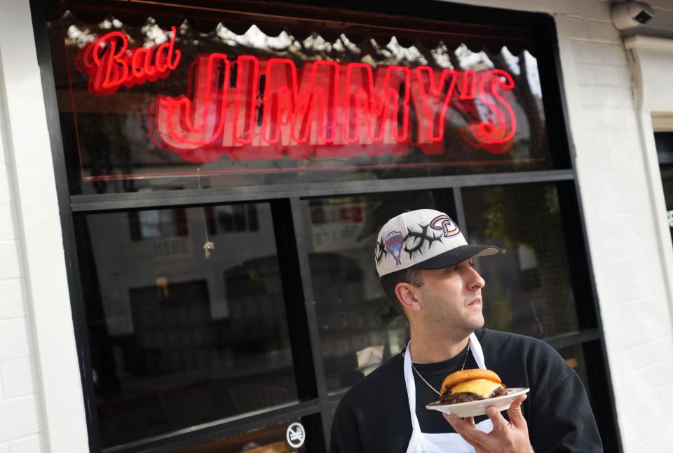 James Piazza, owner of Bad Jimmy's, holds a double burger at Bad Jimmy's in Phoenix on Nov. 28, 2023.