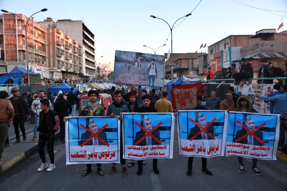 Protesters chant slogans while holding defaced posters in the bottom of newly appointed Prime Minister Mohammed Allawi with Arabic that reads, "Rejected by the people" and "He does not match the specifications of the sit-up squares" during a demonstration in Tahrir Square, Baghdad, Iraq, Sunday, Feb. 2, 2020. Anti-government demonstrators in Iraq rejected Sunday the new prime minister-designate who was recently nominated by rival government factions. Demonstrators have long swore they would not accept a candidate chosen by Iraq's establishment. (AP Photo/Khalid Mohammed)