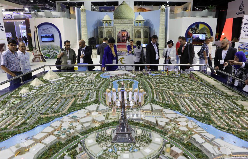 FILE - In this Wednesday, Oct. 9, 2013 file photo, Visitors watch a model for the Falconcity project during the second day of a real estate fair called Cityscape Global in Dubai, United Arab Emirates. A global property consultant said Monday there are worrying signs that Dubai could be facing another economic bubble after property prices jumped more than 22 percent last year and rents by 17 percent. (AP Photo/Kamran Jebreili, File)