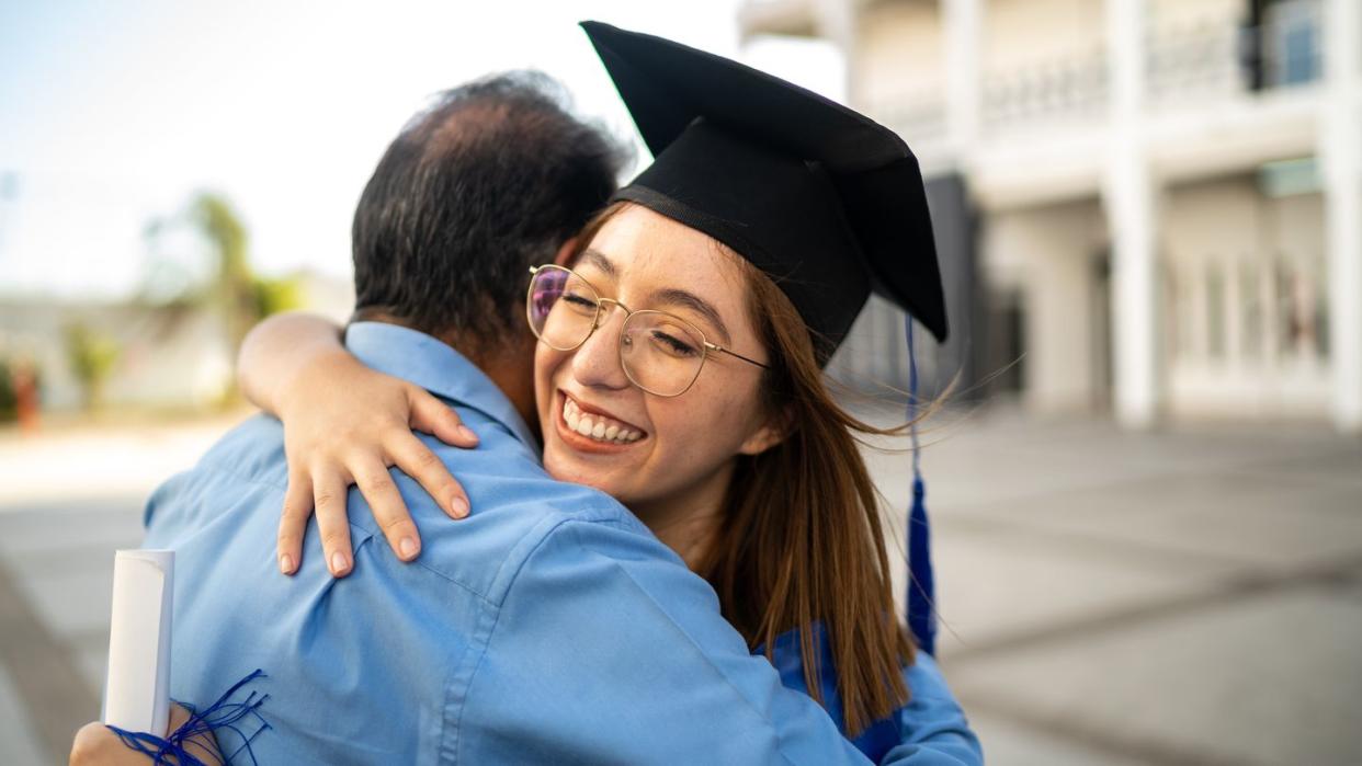 young graduate embracing father on her graduation day