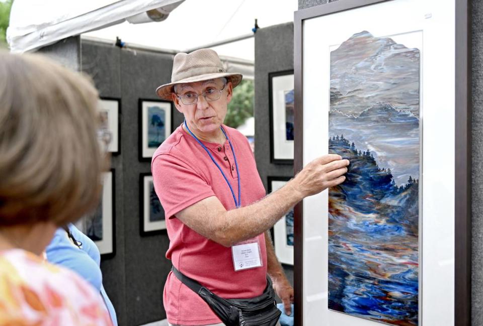 Artist Richard Bond talks to visitors about his sandblasted glass artwork at his both along Burrowes St. at the Central Pennsylvania Festival of the Arts on Thursday, July 11, 2024.