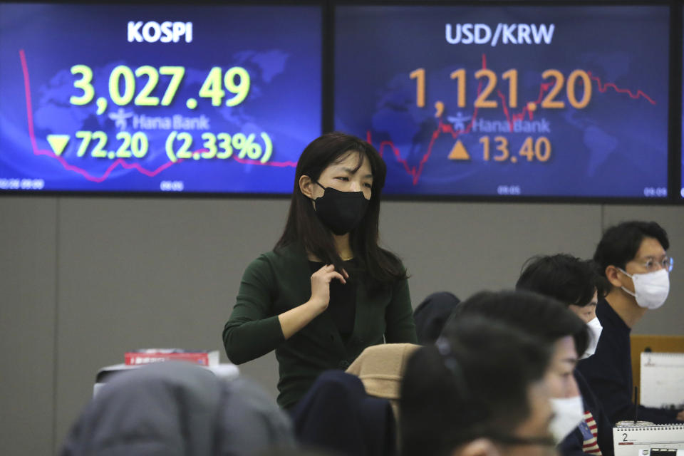 A currency trader walks near screens showing the Korea Composite Stock Price Index (KOSPI), left, and the foreign exchange rate between U.S. dollar and South Korean won at the foreign exchange dealing room of the KEB Hana Bank headquarters in Seoul, South Korea, Friday, Feb. 26, 2021. Asian shares skidded Friday after rising bond yields triggered a broad sell-off on Wall Street that erased the markets gain for the week and handed the Nasdaq composite index its steepest loss since October. (AP Photo/Ahn Young-joon)