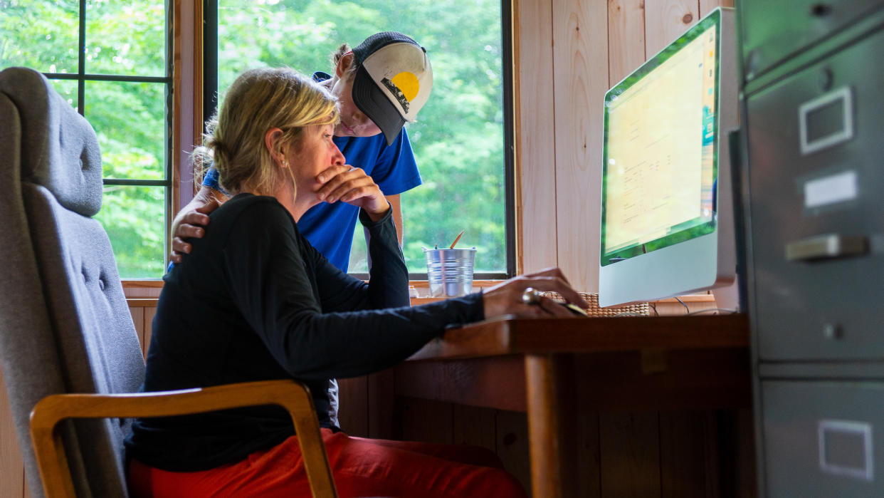 A mother and son at home looking at a computer screen.