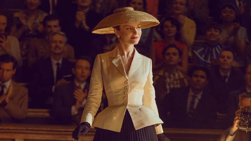 Dior's iconic “Bar” suit, consisting of a full black skirt and voluminous cream blazer that emphasizes the waist and shoulders, with an accompanying wide-brimmed hat, has been copiously referenced in fashion and pop culture. - Roger Do Minh/Apple TV+