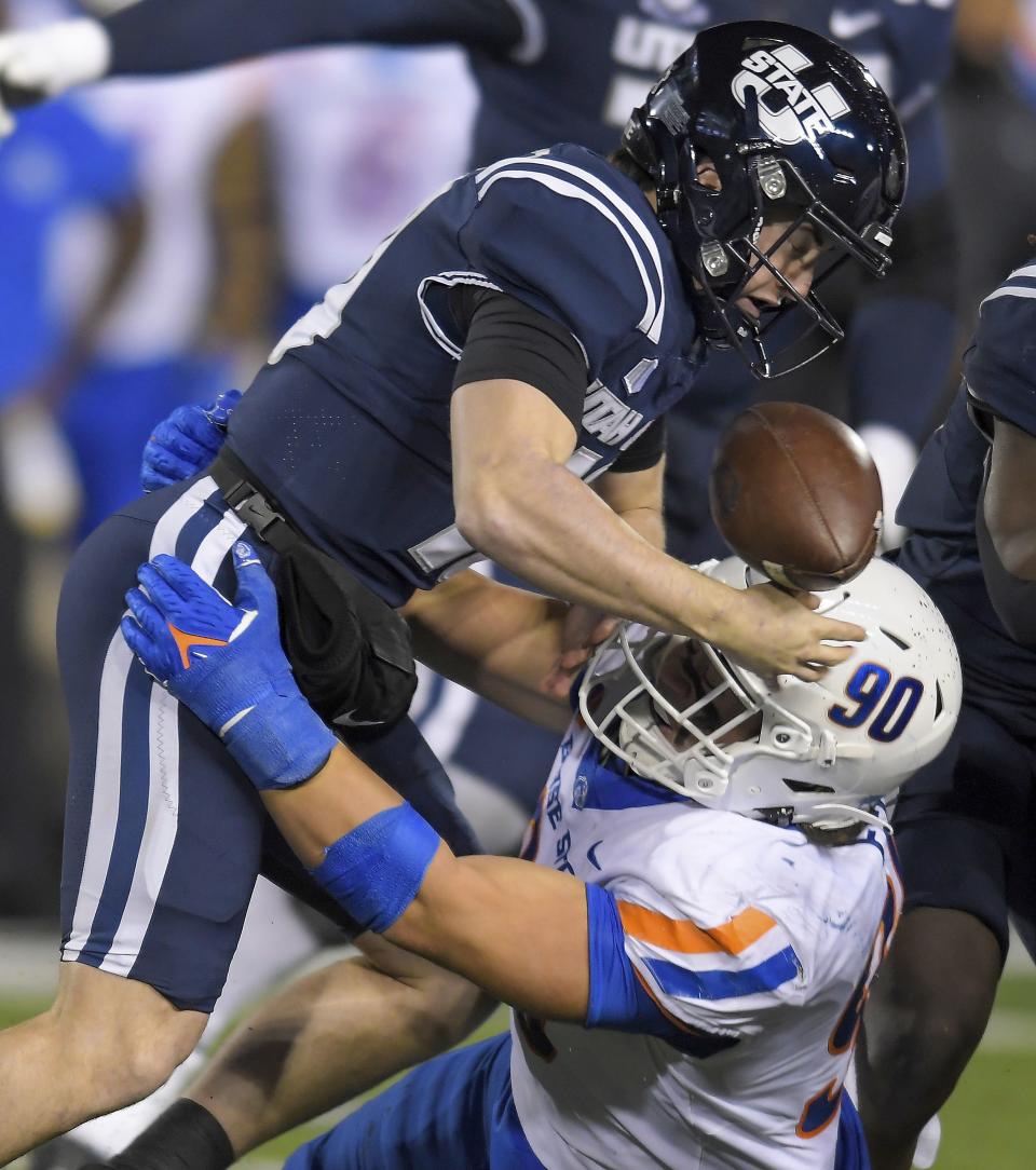 Utah State quarterback McCae Hillstead, top, fumbles after being hit by Boise State defensive tackle Braxton Fely (90) in the first half of an NCAA college football game Saturday, Nov. 18, 2023, in Logan, Utah. | Eli Lucero/The Herald Journal via AP