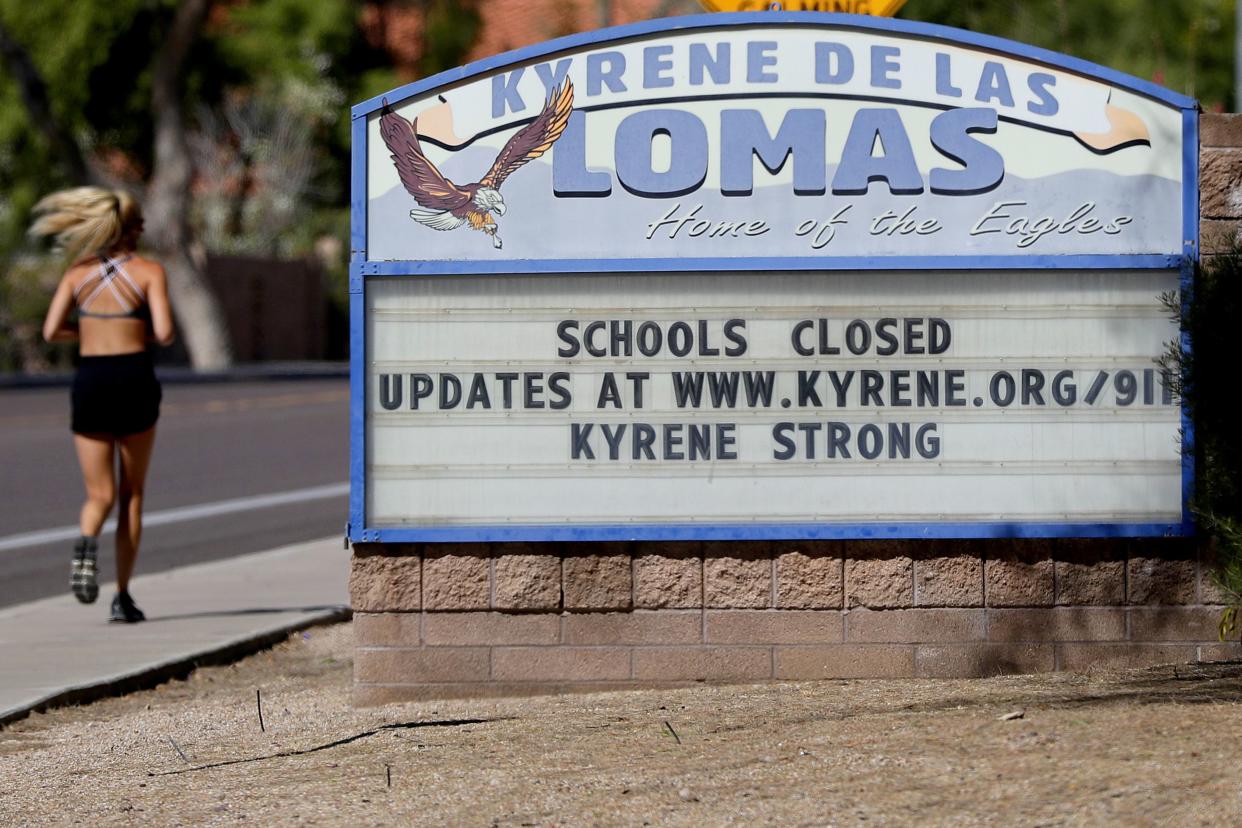 A runner passes a school closed sign on Friday, April 24, 2020, in Phoenix, Arizona. It took a decade for Arizona lawmakers to restore much of the school funding they cut in the wake of the Great Recession. Now, education leaders fear a looming recession created by the coronavirus could once again mean reductions in school funding.