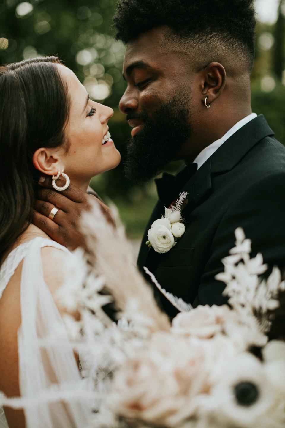 A bride and groom lean together and smile at each other on their wedding day.