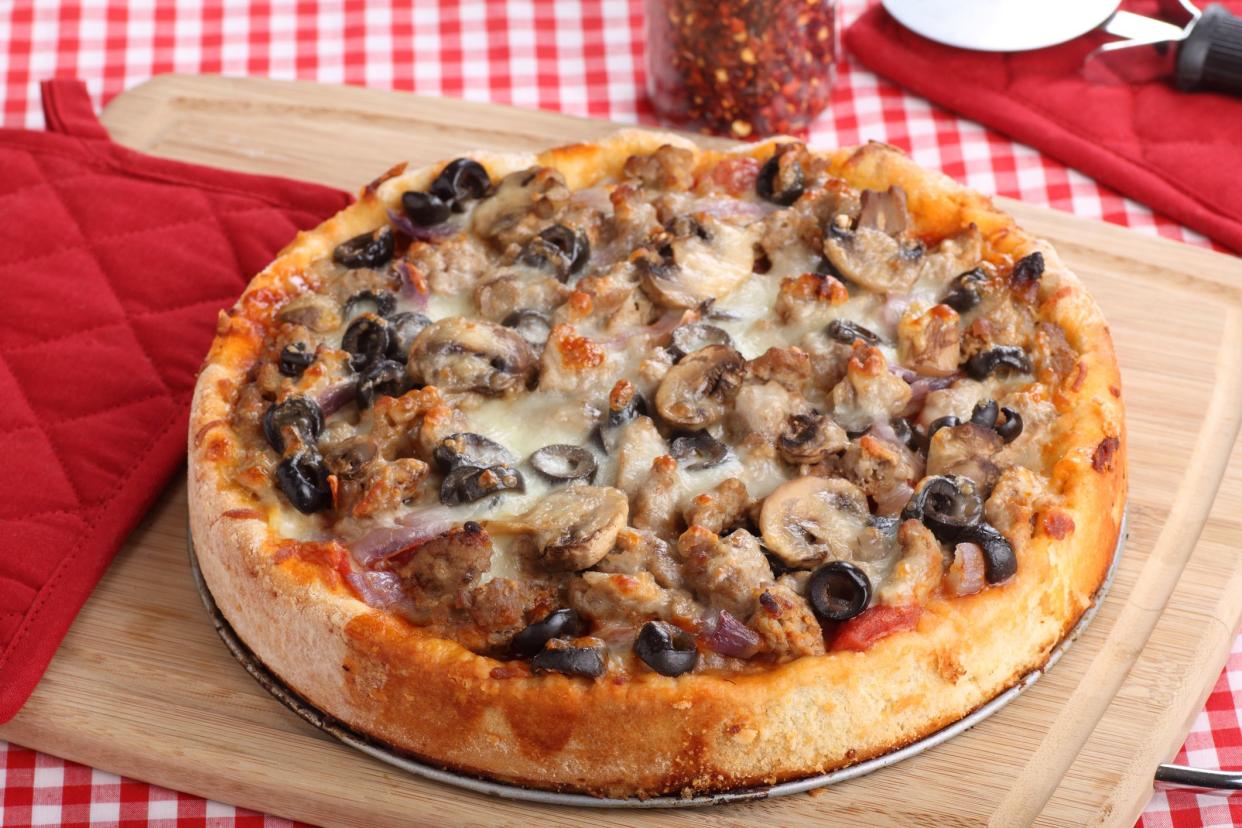 Deep dish pizza topped with sausage, mushrooms and black olives