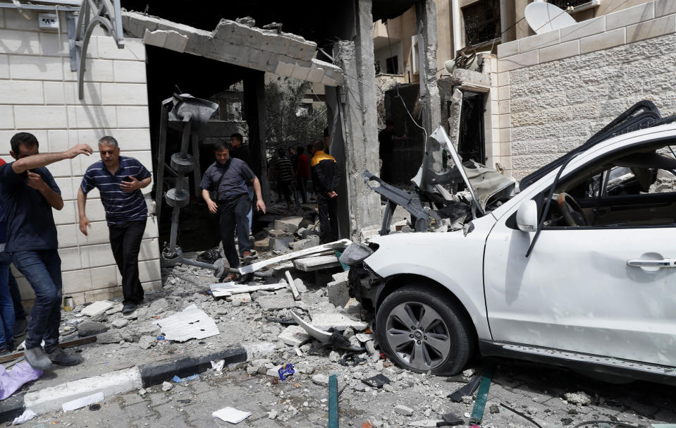 People inspect destroyed cars and the rubble of residential building which was hit by Israeli airstrikes, in Gaza City, Thursday, May 20, 2021. (AP Photo/Adel Hana)