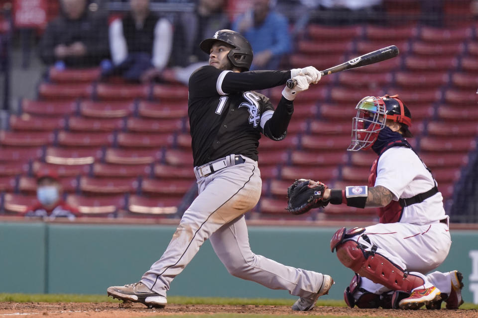 Chicago White Sox's Nick Madrigal, left, hits a sacrifice fly, allowing teammate Leury Garcia to score, as Boston Red Sox's Christian Vazquez, right, looks on in the sixth inning of a baseball game, Sunday, April 18, 2021, in Boston. The game is the second of a doubleheader Sunday. (AP Photo/Steven Senne)