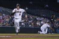 Arizona Diamondbacks' Carson Kelly runs to home plate to score a run against the San Francisco Giants as Diamondbacks third base coach Tony Perezchica (3) signals to a base runner and umpire Ramon De Jesus (18) looks on during the first inning of a baseball game, Thursday, Aug. 5, 2021, in Phoenix. (AP Photo/Ross D. Franklin)