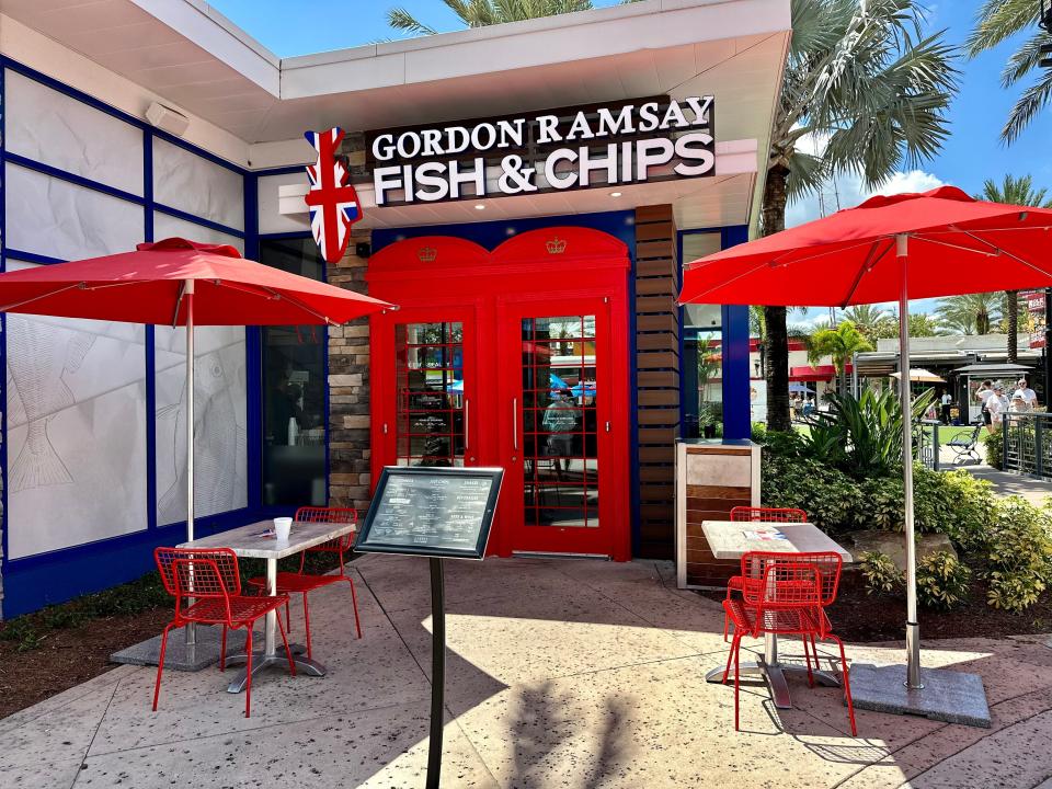 The entrance to Gordon Ramsay Fish and Chips, with red doors and umbrellas.