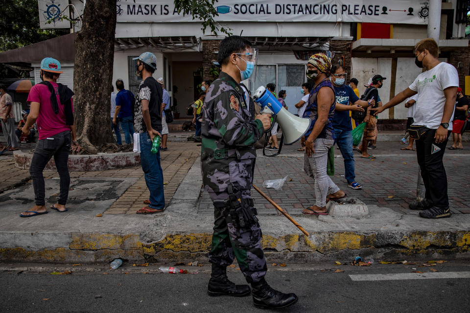 A police officer reminds homeless people to practice social distancing as they queue to receive free meals distributed by members of the Society of the Divine Word (SVD) on Dec. 15, 2020 in Manila.<span class="copyright">Ezra Acayan—Getty Images</span>