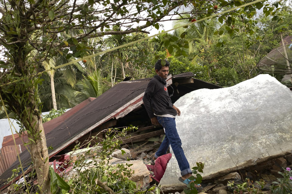 A man walks past a damaged house following an earthquake in Talamau, in West Pasaman district, West Sumatra, Indonesia, Friday, Feb. 25, 2022. The strong and shallow earthquake hit off the coast of Indonesia's Sumatra island on Friday, panicking people in Sumatra island and neighboring Malaysia and Singapore. (AP Photo/Suryo Wibowo)